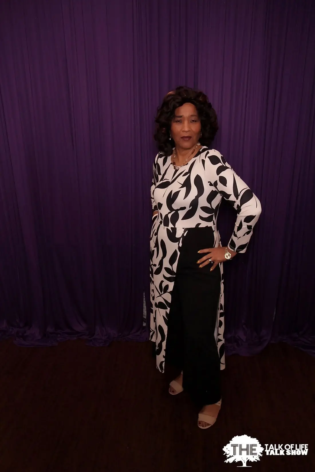 Elma posing in front of The Talk of Life purple studio backdrop