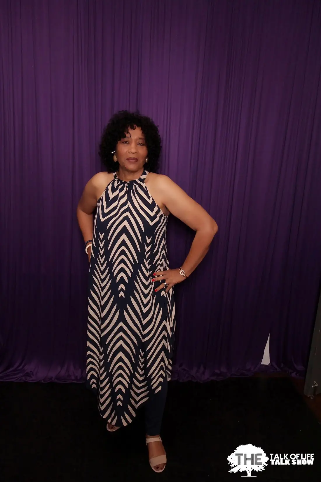Elma in a patterned dress on the talk show set